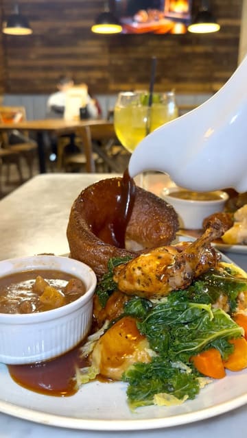 The creator visits Nova Scotia in Liverpool to review their Sunday roast offering. The video features a walkthrough of the venue, highlighting the cozy interior and the view, followed by a detailed look at the roast chicken and nut roast dishes, including a gravy pour and a dessert finish.