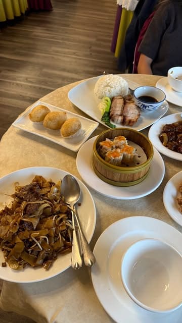 A short montage showcasing a variety of dishes at Dragon's Delicacy, including dumplings, stir-fried ho fun, and roast meats, filmed in a casual dining setting.