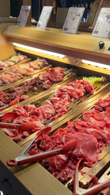 A video tour of a hotpot and BBQ restaurant in Leicester, showcasing the buffet selection of raw meats, vegetables, and sushi, as well as the individual cooking stations at each table.