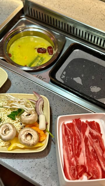 A montage-style video showcasing the hotpot and BBQ dining experience at DAIU in Cardiff Bay. The video highlights the variety of raw ingredients available at the buffet, including meats, seafood, and vegetables, as well as the sauce station and the interactive cooking setup at the tables.
