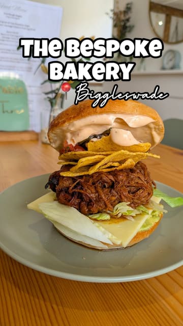 A review of The Bespoke Bakery in Biggleswade, highlighting their homemade cookies, iced lattes, and bagels. The video features the creator trying the food and giving a tour of the cozy interior.