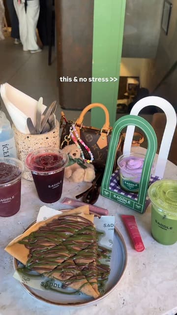 A short, aesthetic montage showcasing various drinks and a crepe at Saddle London, emphasizing the visual appeal of the products and the cafe's location near Harrods.