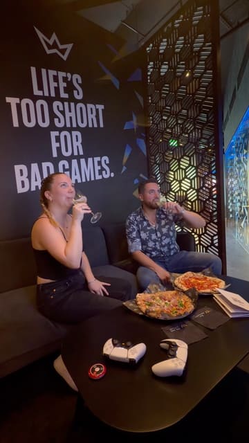 The video features a couple visiting XP Tavern, a gaming-themed bar. It highlights the atmosphere, the food (specifically pizzas), and the gaming experience, showing them enjoying drinks and playing on a PlayStation 5.