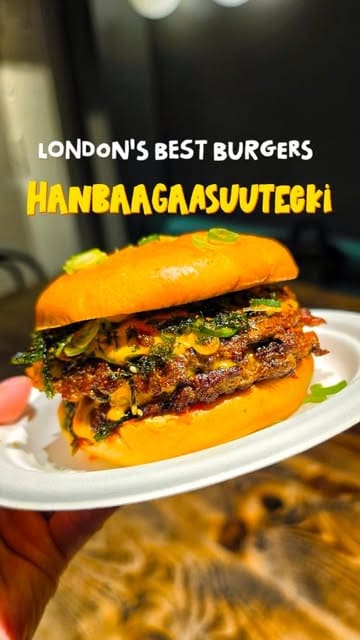 A food review vlog featuring a visit to a burger venue called Hanbaagaasuuteeki. The creator tries several burgers, including a chorizo burger and a chicken foie gras burger, as well as a prawn dish and frozen drinks. He provides commentary on the flavors and textures of the food.