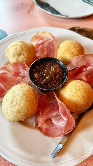 A food review video featuring a creator visiting an Italian restaurant in Glasgow. The video focuses on a specific starter dish consisting of dough balls, prosciutto, and fig jam, with the creator and a companion tasting and reviewing the food.