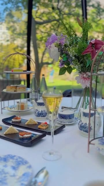 A montage showcasing an afternoon tea experience at the London Secret Garden, located at the DoubleTree by Hilton Kensington. The video highlights the private glass dome dining pods, the table setting, and the various food items served, including sandwiches, scones, and desserts.