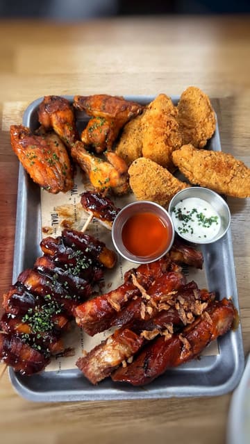 A promotional video for The Dial in North Greenwich, featuring shots of the venue's interior, bar area, and a selection of their sharing-style food menu including a meat platter, wagyu burger, and chicken schnitzel.