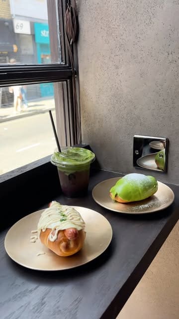 A short, aesthetic promotional video for a new Korean cafe in Soho called Tokkia, highlighting their signature salt bread pastries and matcha drinks, including a unique serving window feature.