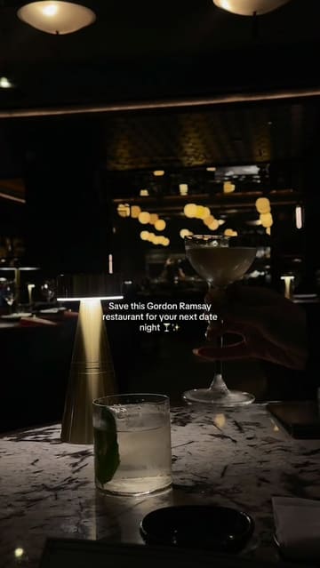 A short, cinematic montage showcasing the interior and food offerings of Lucky Cat by Gordon Ramsay in Mayfair. The video features slow-motion shots of cocktails, sushi, robata-grilled dishes, and dessert, set to music with text overlays highlighting the restaurant's suitability for date nights.
