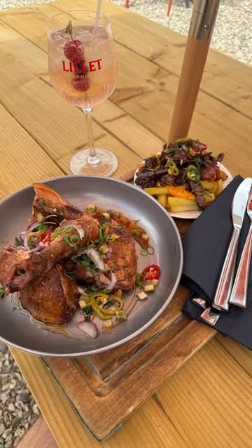 A short, static-heavy video showcasing a meal of hot honey chicken and beef loaded fries, accompanied by a Lillet spritz, at an outdoor venue.