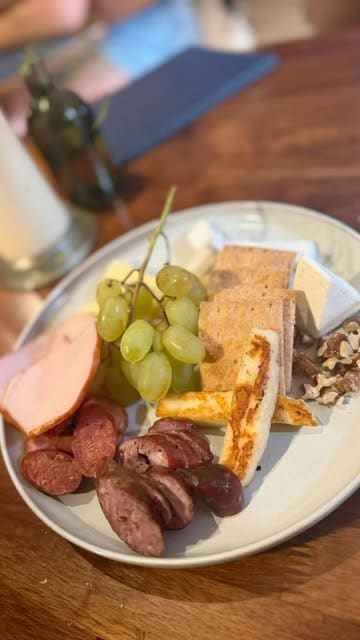 A montage video showcasing a Greek wine tasting experience at a wine bar, featuring various wines, a charcuterie board, and a beef stifado dish.