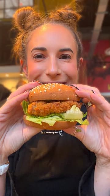 A creator reviews the new gluten-free fried chicken burger and Aji Verde sauce at Leon, highlighting the taste and dietary suitability.