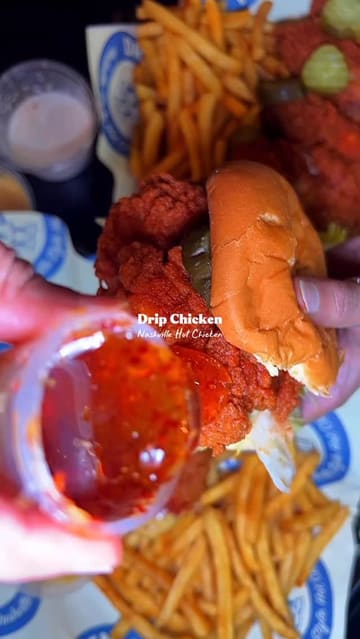 A montage of Nashville hot chicken dishes, including sandwiches, tenders, wings, and a smash burger, filmed with high-quality close-ups to emphasize texture and sauce. The video features a clean, polished aesthetic with minimal text overlays identifying the venue.