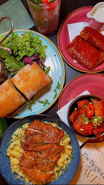 A promotional reel for Wonderlust Bistro in Oldham, showcasing a variety of dishes including steak sandwiches, pasta, Korean corn dogs, and desserts, alongside glimpses of the venue's interior.