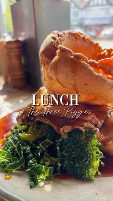 A montage of various dishes and cocktails served at The Three Piggies, including a Sunday roast, burger, and desserts, set to music with text overlays identifying the items.