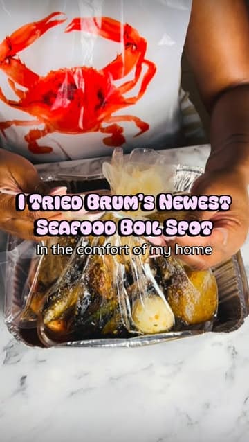 A creator reviews a seafood boil takeaway service in Birmingham, showcasing the contents of the meal, including lobster, prawns, and sides, while providing commentary on the quality and flavor.