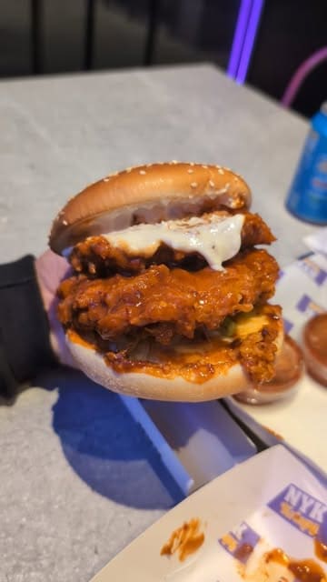 A short review of a new fried chicken spot in Birmingham, featuring a close-up of their signature spicy chicken burger and a look at the venue's exterior.