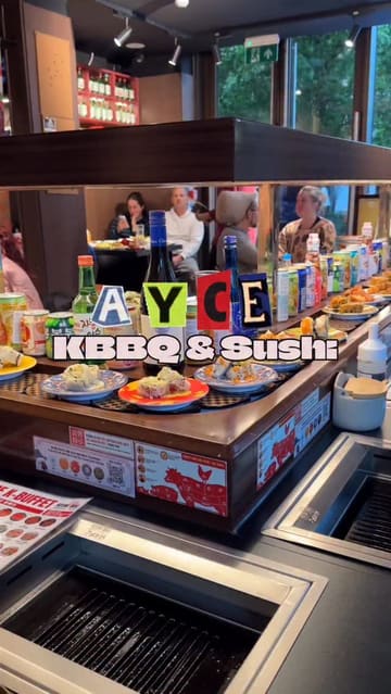 A short, punchy reel showcasing an All-You-Can-Eat Korean BBQ and sushi restaurant. The video highlights the unique dining format, featuring a conveyor belt for sushi and drinks alongside personal tabletop grills for cooking meat.