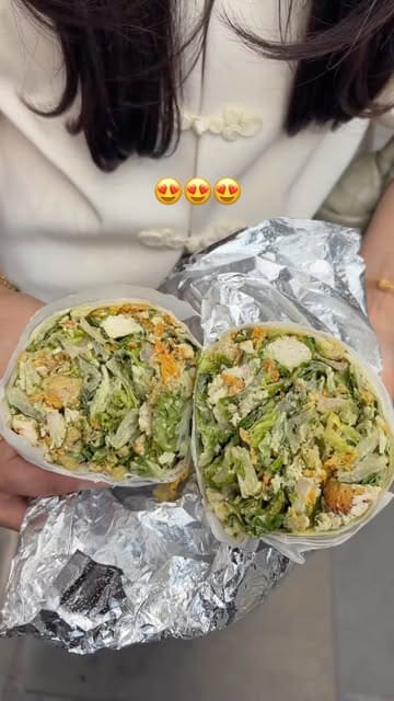 Two creators visit a new branch of Czer to try their viral Caesar salad wrap, documenting the ordering process, the unique addition of crisps to the wrap, and their taste test reaction.