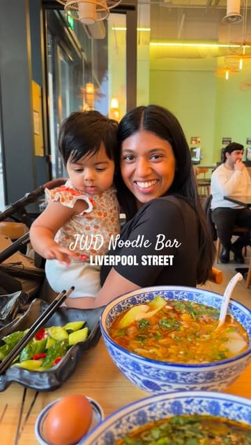A short, engaging video review of JWD Noodle Bar in Liverpool Street, London. The video features the creator and their child, highlighting the fresh hand-pulled noodle process, the restaurant's interior, and a variety of dishes including noodle soup and skewers.