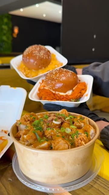 A montage-style video showcasing various chicken-based dishes from Peck'd in Bury, including burgers, loaded fries, and rice bowls. The video features close-up shots of the food being dipped in sauces, alongside brief glimpses of the venue's interior and menu board.