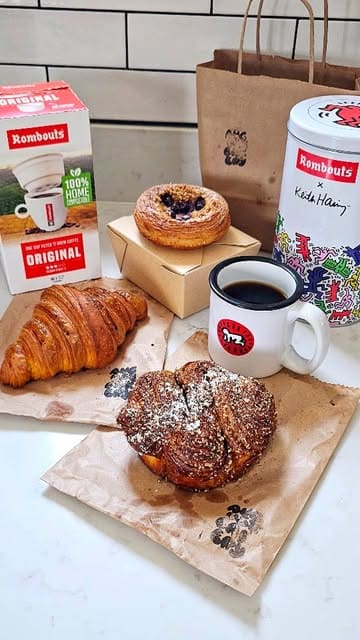 A short, handheld video demonstrating the preparation of a Rombouts single-cup filter coffee at home, paired with various pastries.