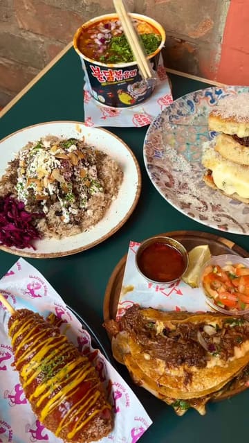 A montage of various food items from different vendors at a food hall, featuring close-up shots of birria ramen, tacos, a focaccia sandwich, a lamb rice box, a Korean hot dog, and taco pancakes.