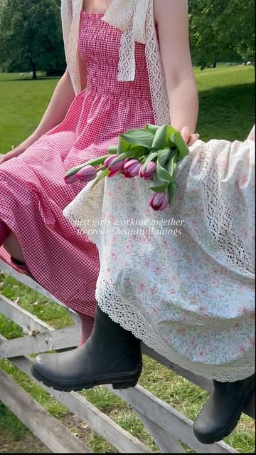 A group of friends in cottage-core attire enjoy a picnic and visit a picturesque country venue. The video features shots of them posing, taking photos, drinking champagne, and eating cake in a garden and an indoor dining area.