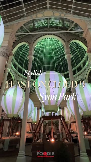 A montage video showcasing the 'Feast on Cloud 9' dining experience at Syon Park's Great Conservatory. The video highlights the unique hot air balloon-themed dining pods, the elegant conservatory setting, and various courses of the meal, including starters, mains, and desserts.