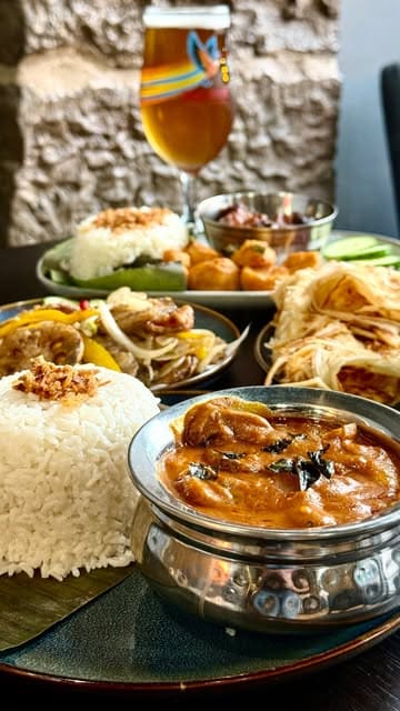 A short, punchy reel showcasing a variety of Malaysian dishes including curries, roti, and lotus root at Wok and Sambal. The video uses quick cuts to highlight the textures and presentation of the food, interspersed with a brief shot of the restaurant's interior.