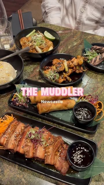 A short montage showcasing various Asian fusion dishes and cocktails at The Muddler in Newcastle, featuring close-up shots of pork belly, spring rolls, and skewers.