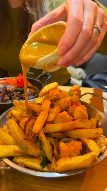 A fast-paced promotional video for Mans Market, a Chinese restaurant in Leeds. The video features close-up shots of various dishes like crispy chilli beef, noodles, and loaded fries, alongside glimpses of the restaurant's vibrant interior, neon signage, and the unique 'Feed Me' ordering menu. The creator provides a voiceover highlighting a January discount offer.