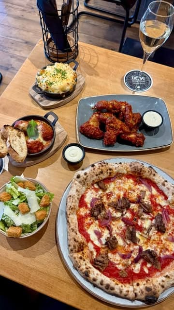 A short, visually appealing montage showcasing the exterior and various dishes at Base Pizzeria & Bar, including pizza, meatballs, mac and cheese, and chicken wings.