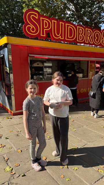 A mother takes her two children and their dog to a baked potato stall called Spud Bros in Preston. The video follows their journey to the stall, shows the menu, and captures their reactions to the food while eating in the car.