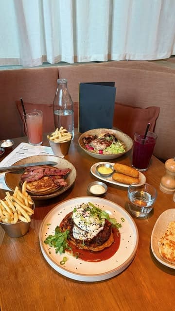 A short montage video showcasing a brunch spread at Caravan King's Cross, featuring close-ups of pancakes, croquettes, buttermilk chicken, and drinks, alongside brief shots of the restaurant interior and the canal-side exterior.