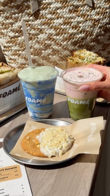 A short, aesthetic montage showcasing the menu at Foamé cafe in Birmingham, featuring close-ups of sandwiches, cold foam matcha and smoothie drinks, and a white chocolate macadamia cookie.