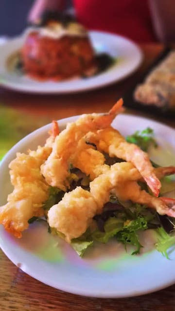 A montage-style video showcasing various Korean dishes including king prawn tempura, seaweed rolls, and bibimbap, alongside shots of the restaurant's interior, specifically the hanging umbrella decor.