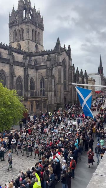 A video capturing the Tartan Parade in Edinburgh, featuring pipe bands, drummers, and Highland dancers performing on the Royal Mile near St Giles' Cathedral.