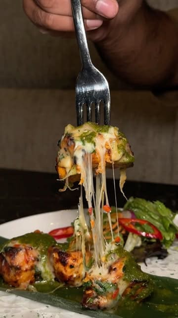 A high-quality food montage showcasing various dishes including lamb shank, chicken skewers, beef skewers, and pan-fried salmon at a restaurant in Manchester.