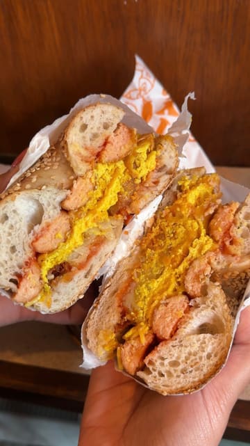 The creator visits Best Boy Bagels and Forge Bakehouse in Sheffield as part of a vegan guide series. The video features close-ups of various bagels, pastries, and coffee, along with shots of the venue interiors and the creator trying the food.