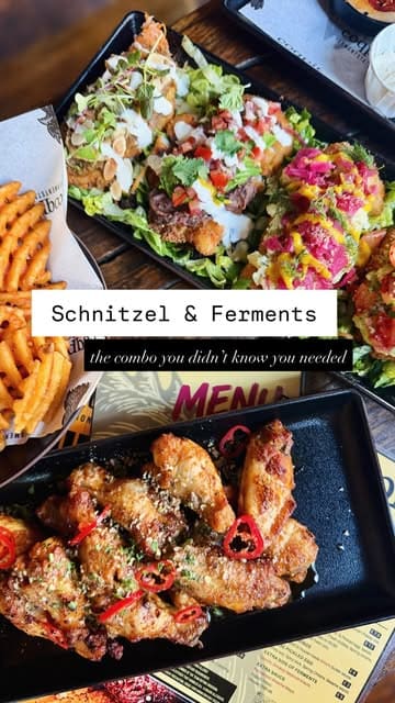 A short, snappy reel showcasing a variety of chicken schnitzel dishes, sides, and fermented drinks from a pop-up venue called Coqpit. The video features close-up shots of the food, including a sharing platter, waffle fries, and a kimchi cheese toastie.