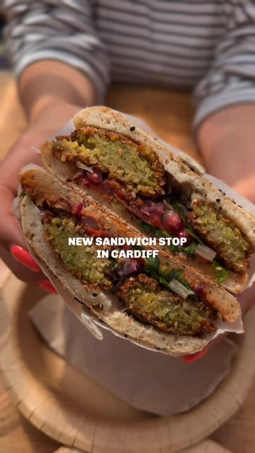 A short, casual vlog-style video showcasing a new sandwich shop in Cardiff called Lahmacun, featuring falafel sandwiches, beer, and cookies in an outdoor seating area.