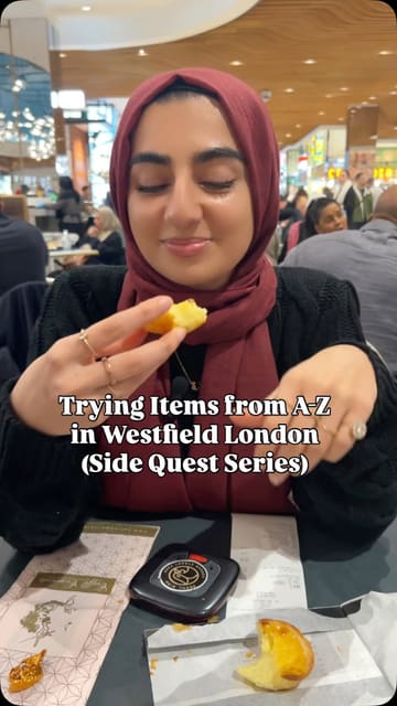 A creator attempts an A-Z food challenge at Westfield White City, visiting various cafes and eateries to try different items. The video features the creator's reactions and reviews of each item, including chocolates, puddings, pastries, frozen yogurt, bubble tea, and Korean street food.