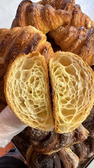 A behind-the-scenes 'day in the life' video showing the preparation process at a bakery. The creator walks through making sourdough, donuts, brownies, and sausage rolls, highlighting the manual effort and craft involved in the daily prep. The video concludes with a personal clip of the creator wakeboarding.