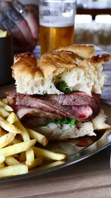 A short montage showcasing the food and setting at Todenham Manor Farm, featuring a beef sandwich, burger, and beer in a rural, outdoor environment.