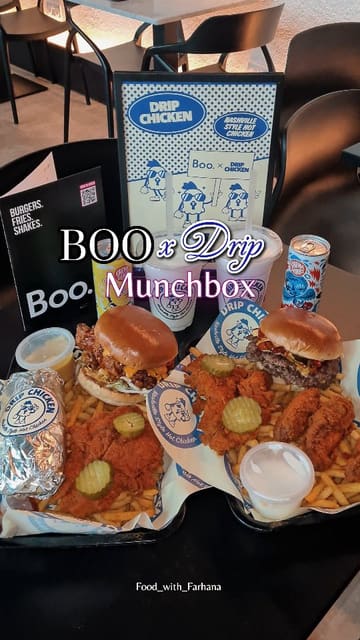 A short-form video showcasing the 'Munchbox' collaboration between Boo and Drip Chicken. The video features close-up shots of burgers, Nashville hot chicken tenders, fries, and drinks, highlighting the textures and sauces. It uses text overlays to identify the collaboration and the items included.