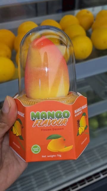 A short, handheld video showcasing a mango-shaped frozen dessert, featuring close-up shots of the packaging and the product itself after a bite is taken.