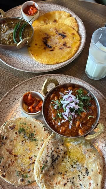 A creator visits Bombay Deli to review their new Desi brunch menu, showcasing the interior, the variety of traditional Indian breakfast dishes, and the lassi.