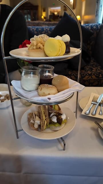 A creator provides a direct-to-camera review of a vegan afternoon tea experience at Whittlebury Park, offering specific feedback on both the savoury and sweet components of the meal.