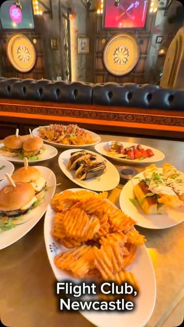 A promotional video for Flight Club in Newcastle, featuring a spread of sharing dishes including burgers, tacos, and nachos, followed by clips of people playing social darts.
